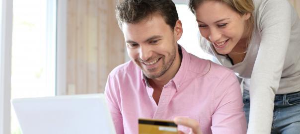 Happy man and woman with a credit card in front of a laptop