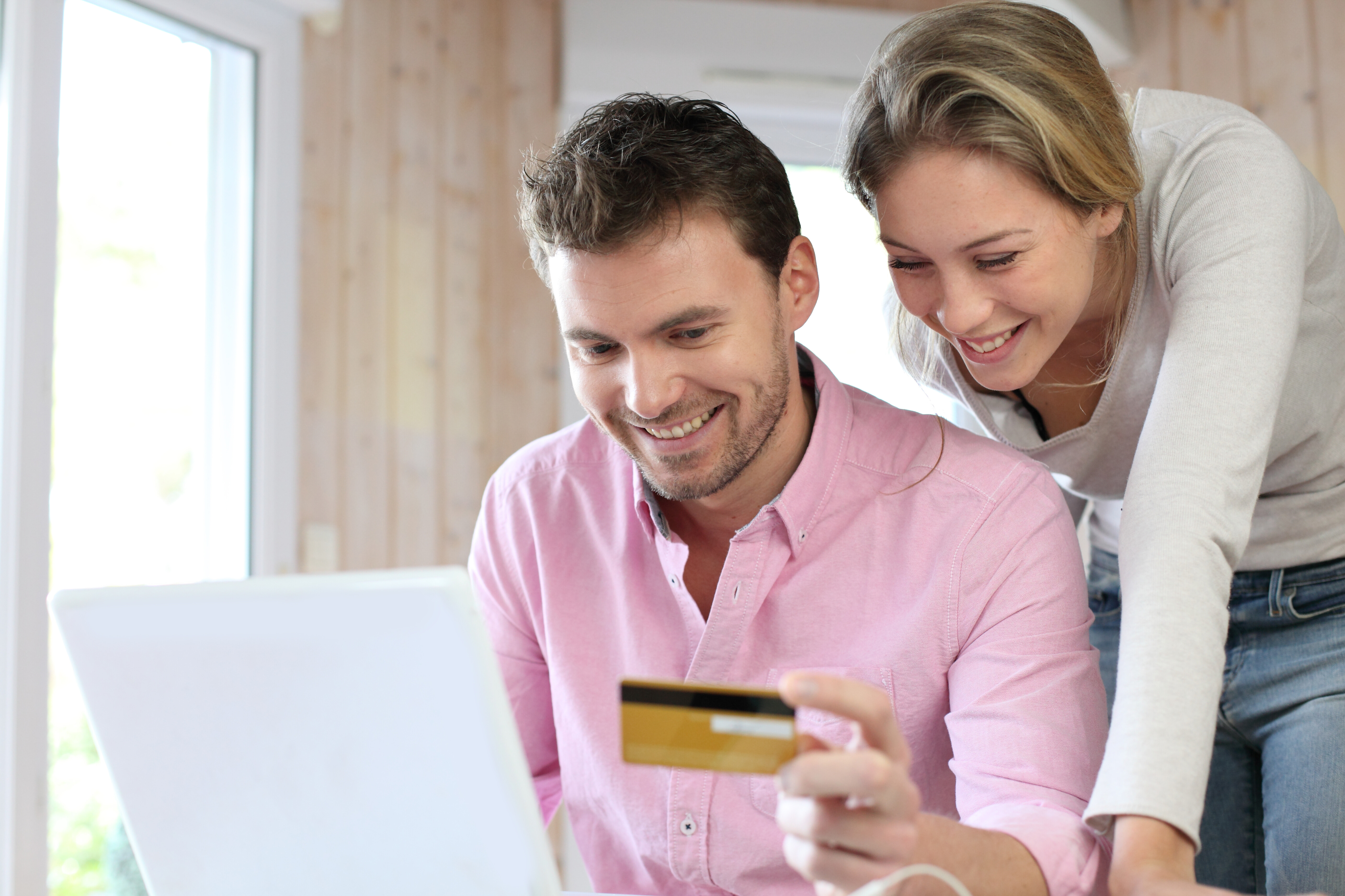 Happy man and woman with a credit card in front of a laptop