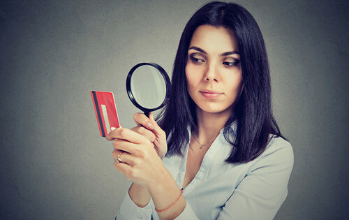 Woman looking through a magnifying glass at a credit card