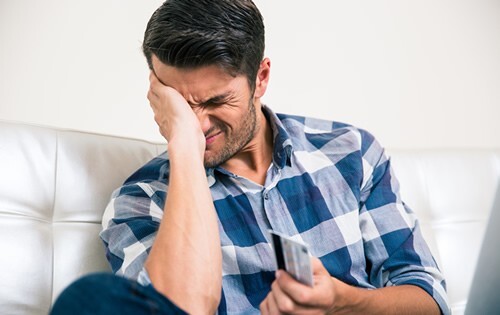 Man holding a credit card and stressed